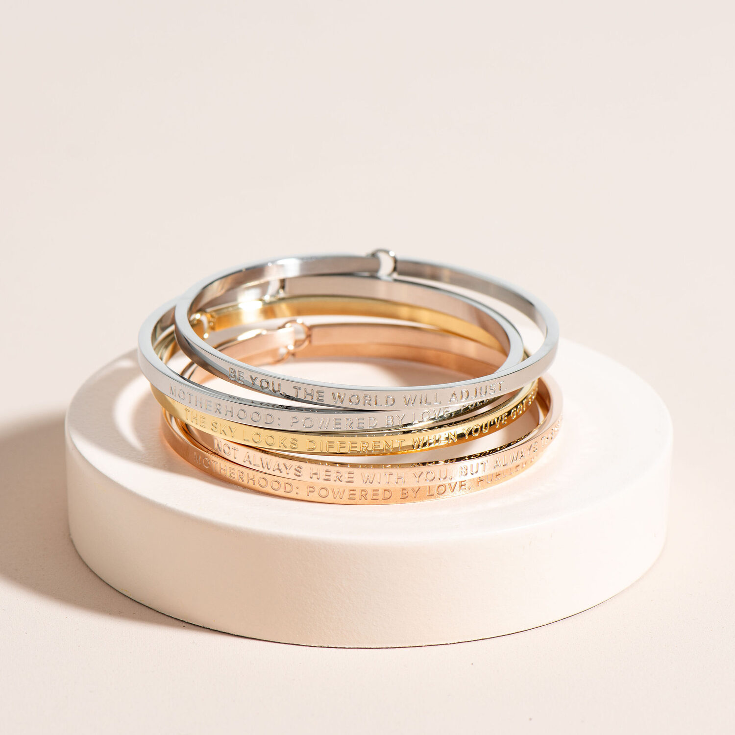 A single BE. Bangle on a soft cream podium.